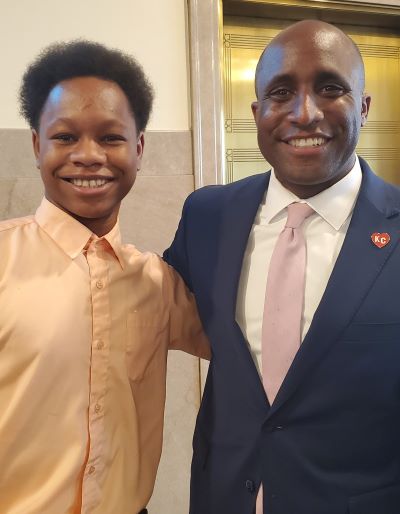 Former SLA Scholar stands next to Kansas City mayor Quinton Lucas with their arms around each other and smiling at the camera